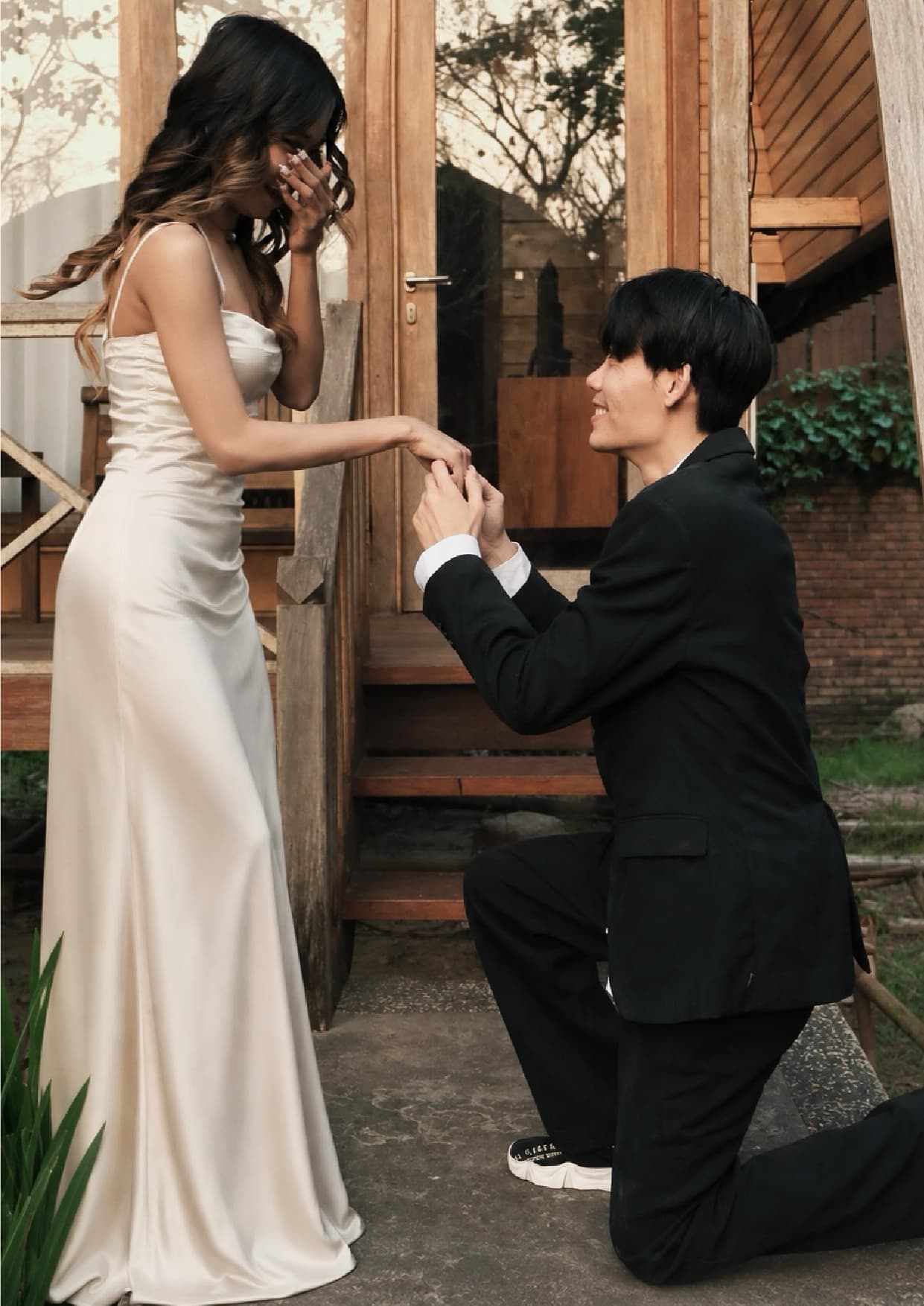 On the step, he kneels and takes her hand